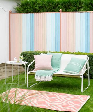 Pretty pastel painted fence with outdoor sofa and rug