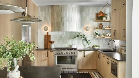 A wooden kitchen with a white tiled backsplash, black countertops, and natural decor