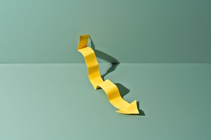 Dud investment trust concept with yellow arrow on green background going downwards