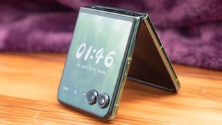 Motorola Razr Plus 2024 in green standing like a tent with a clock on its face