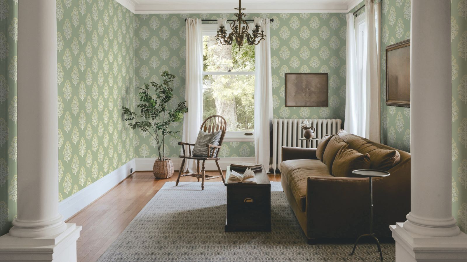 Cozy small living room with hard floors and radiator in view. There is a sofa, ottoman coffee table, and patterned sage wallpaper