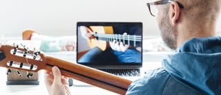 Orange Learn review: Image of man holding guitar watching laptop screen