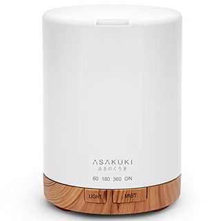 A white cylindrical essential oil diffuser with a wooden effect base