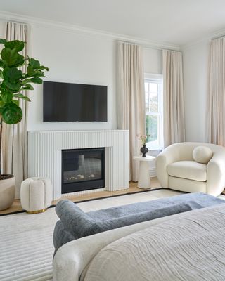 A bedroom with layered textures, a boucle arm chair and fireplace