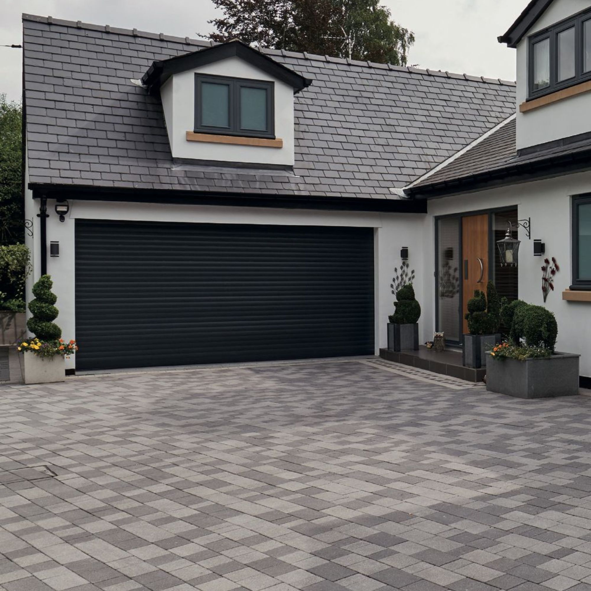 White painted house and garage with driveway block paved in three different shades of grey