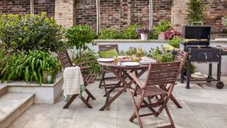 town garden with brick walls and paved seating area with table and chairs