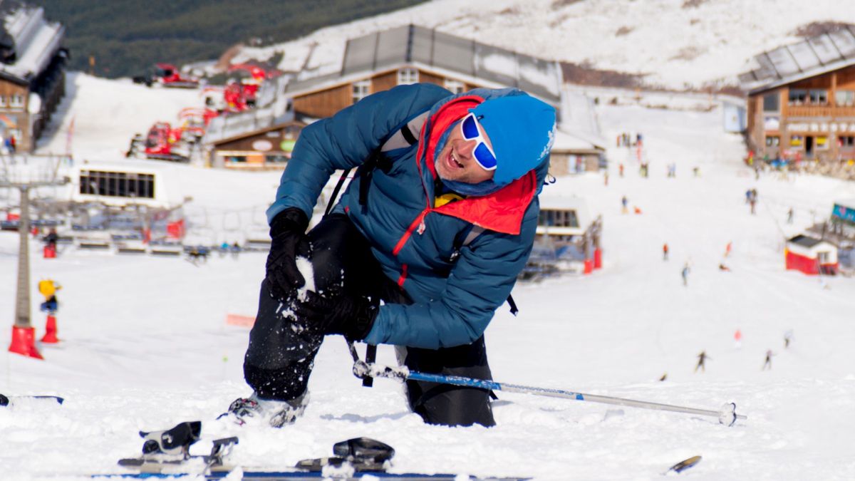 Man lying on snow ski crash injured knee in pain