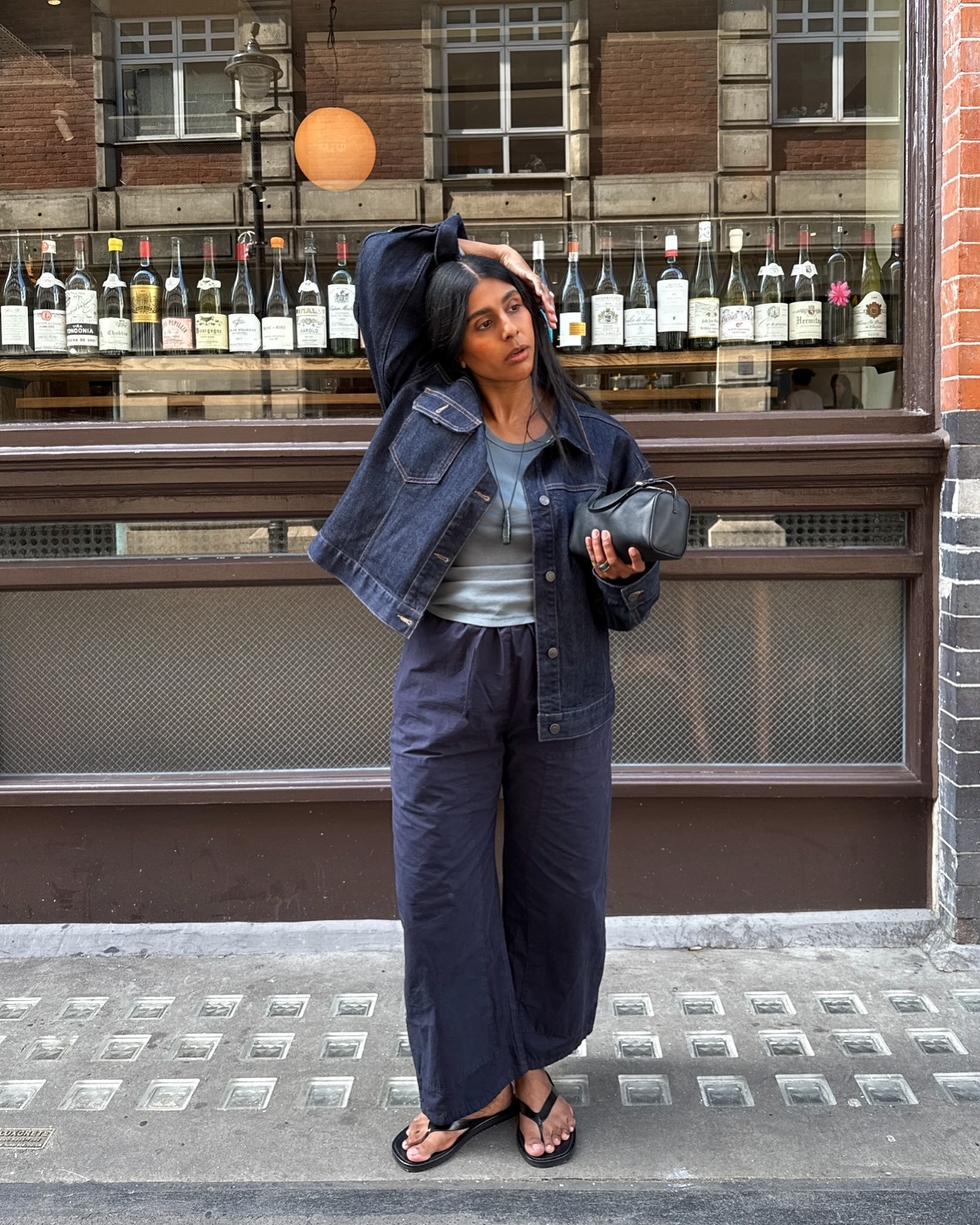 The woman is wearing a denim jacket, cotton pants, and flip-flops.