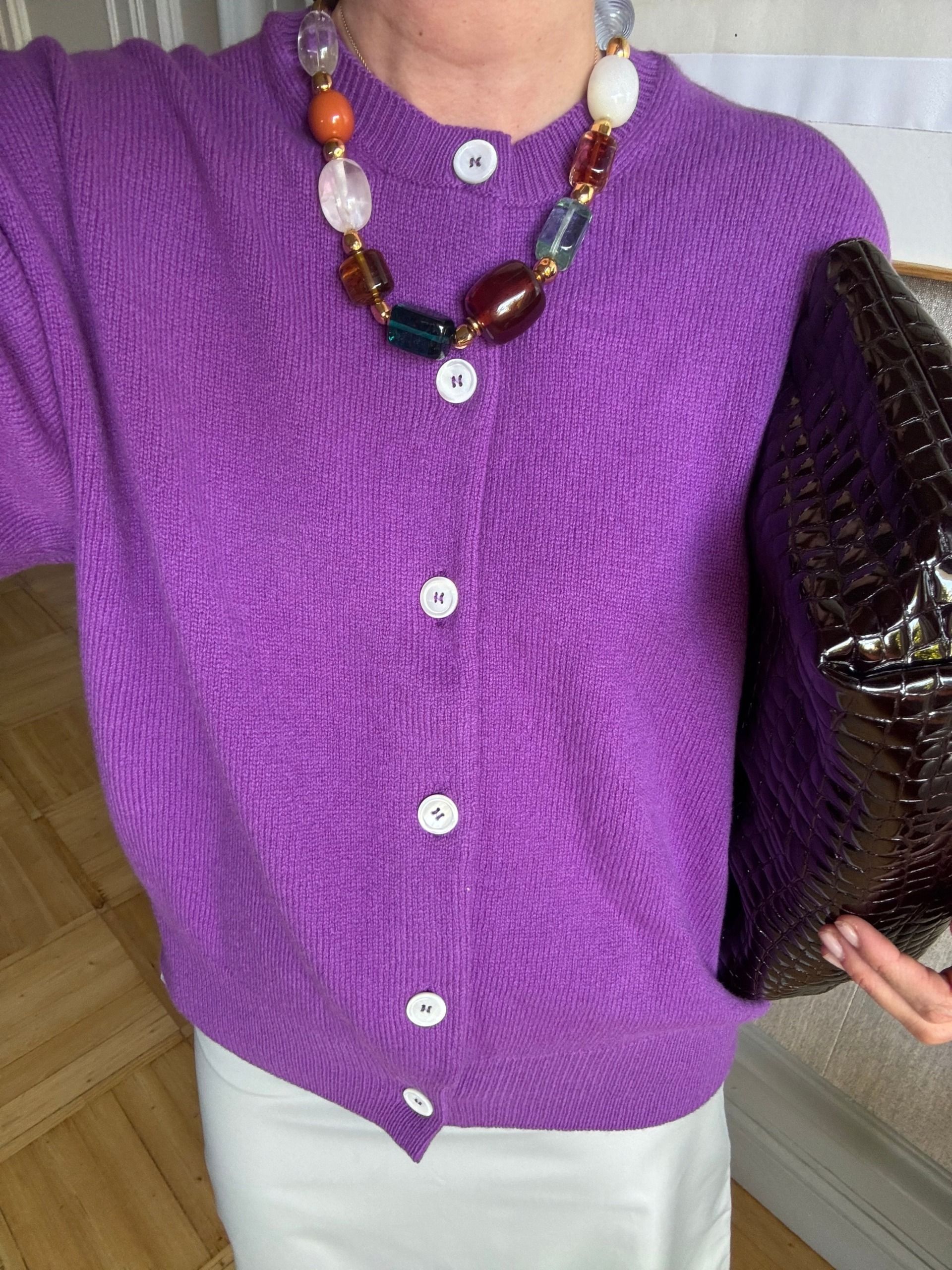 blanca miro wears a purple cardigan, grey skirt, beaded necklace and brown croc clutch