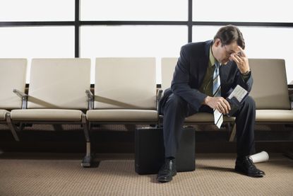 Stressed out businessman sitting in airport.