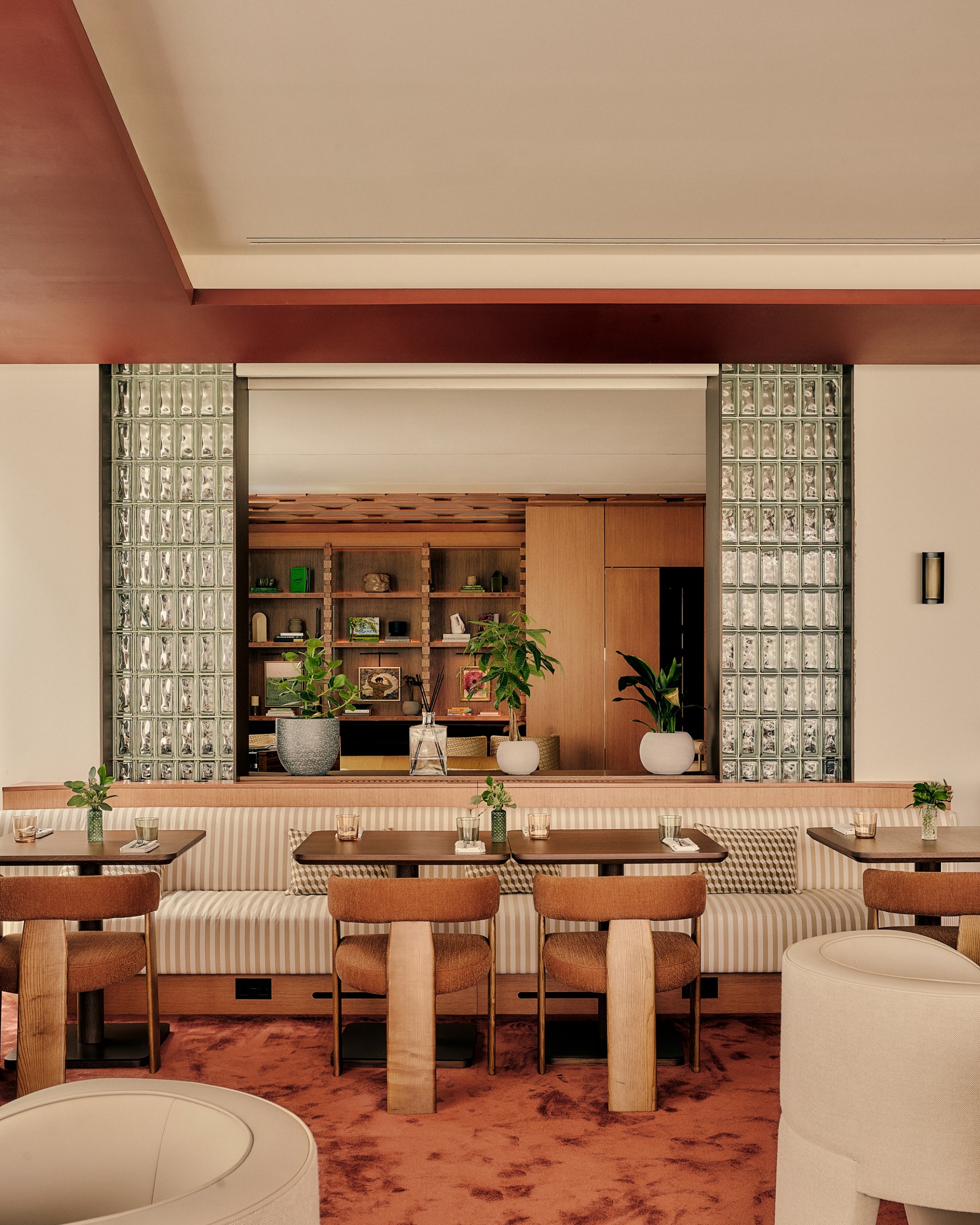 the dining room of the willow room at aethos shoreditch with terracotta carpets, and glass dividers between spaces