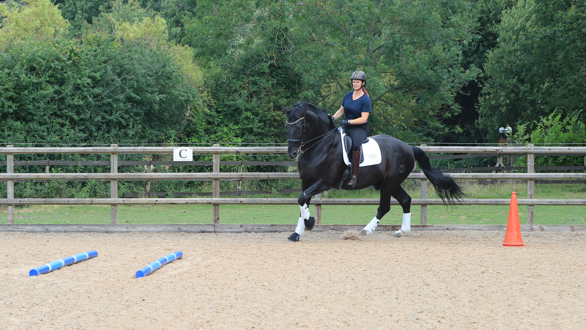 Tania demonstrating the polework exercise to improve centre lines, riding between the cone and poles