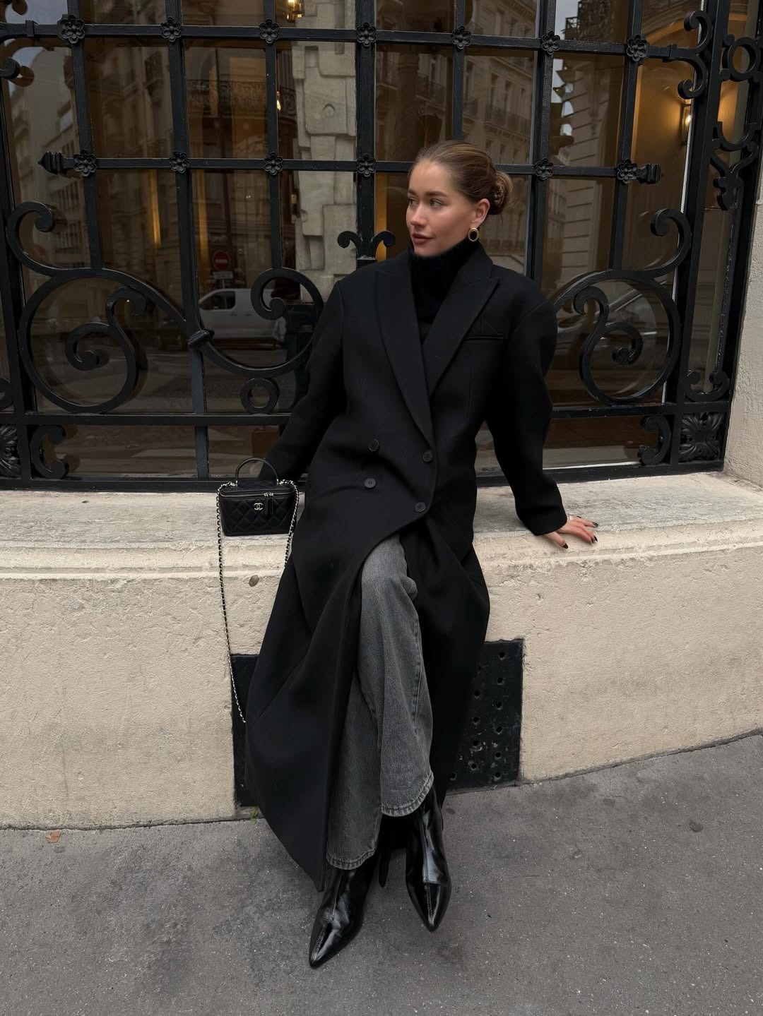 Woman in long black coat and jeans.