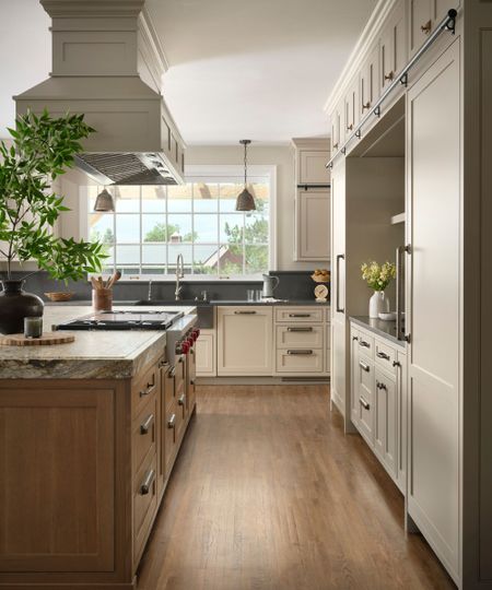 A large kitchen with beige cabinets, a wooden island, marble island countertops, and black granite perimeter countertops