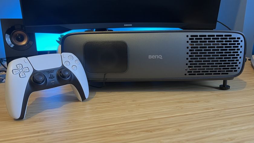 BenQ W4100i projector on a wooden desk with a PS5 DualSense controller