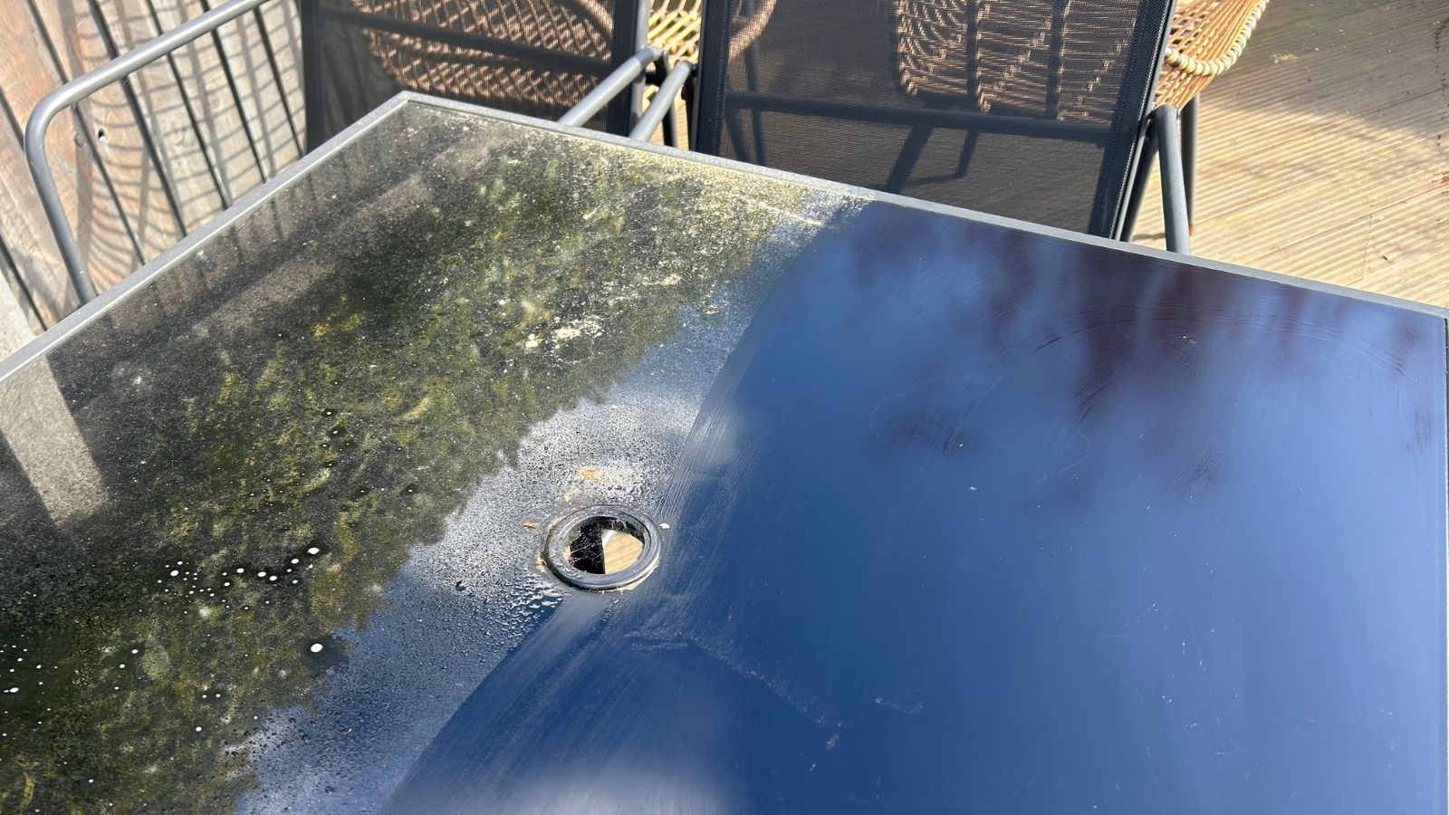 Patio furniture cleaning photo, half of the black glass table clean and the other dirty
