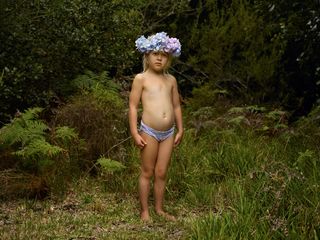 Child wearing flower crown stood in a forest