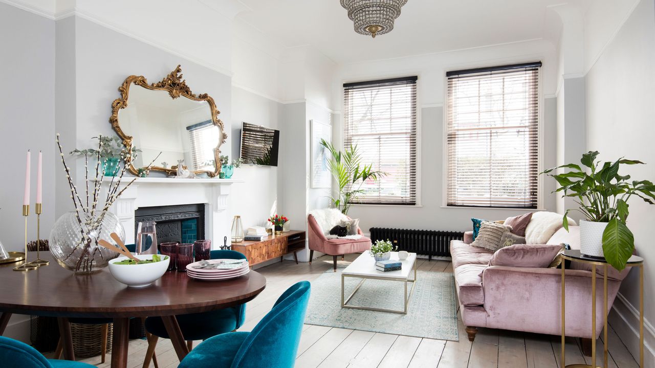 White living room with pink sofa and gold mirror