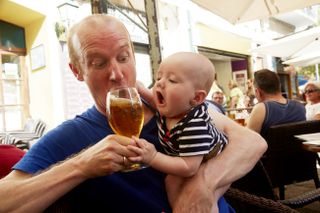 Baby reaching for the pint his dad is drinking