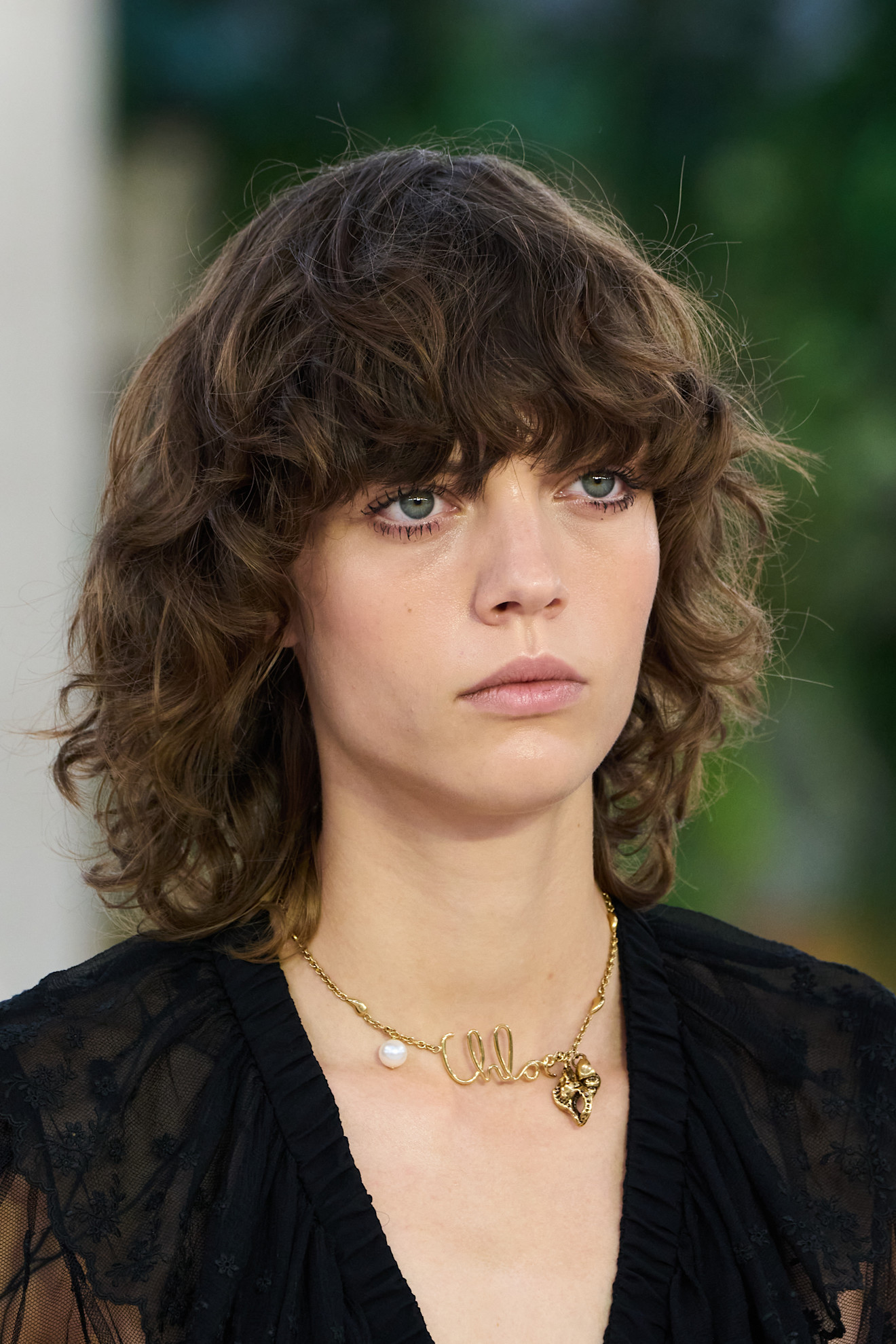 model with a brown shaggy bob haircut and a black jacket