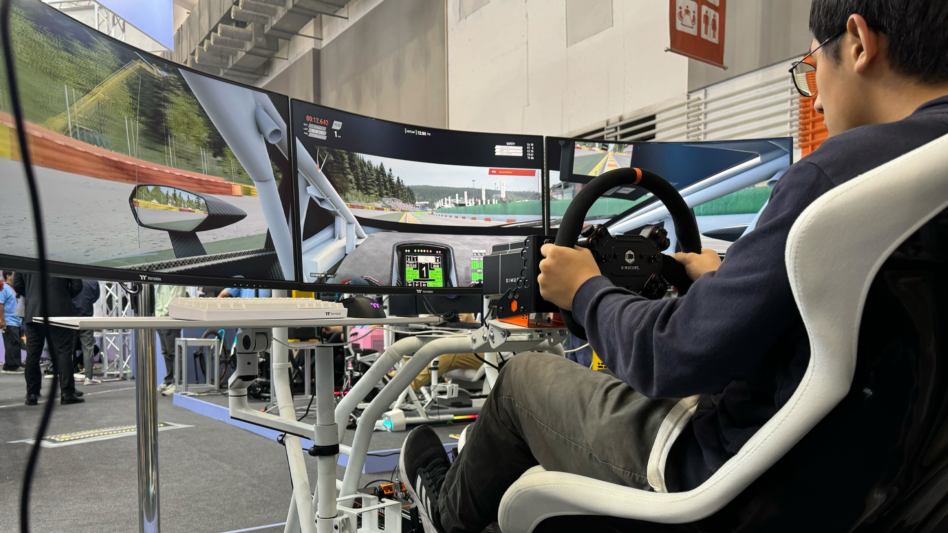 Homme jouant à un jeu de course sur Thermaltake GR500 Racing Sim Cockpit au Computex 2024.