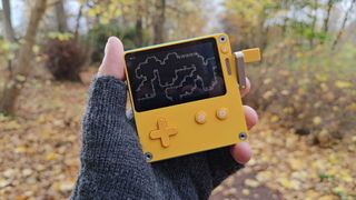 Hand holding Playdate on woodland trail