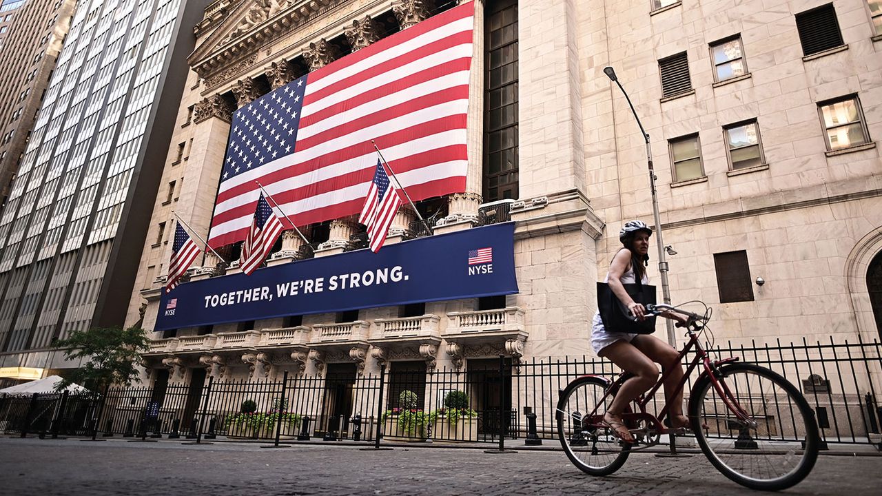 Woman riding a bike past the New York Stock Exchange 