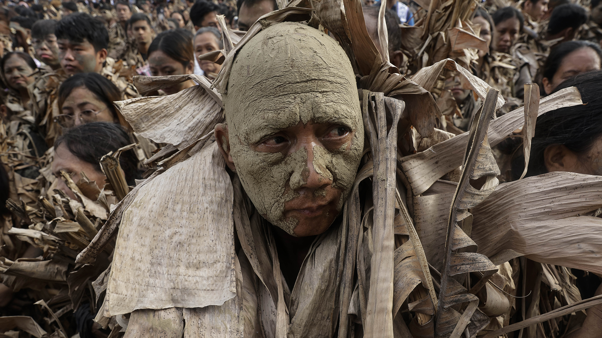 Catholic devotees covered in mud and leaves gather outside a church during the Taong Putik festival in Bibiclat, northern Philippines