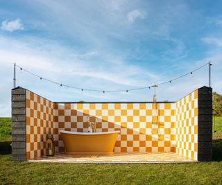 Yellow and white tiled outdoor bathroom with tub and shower
