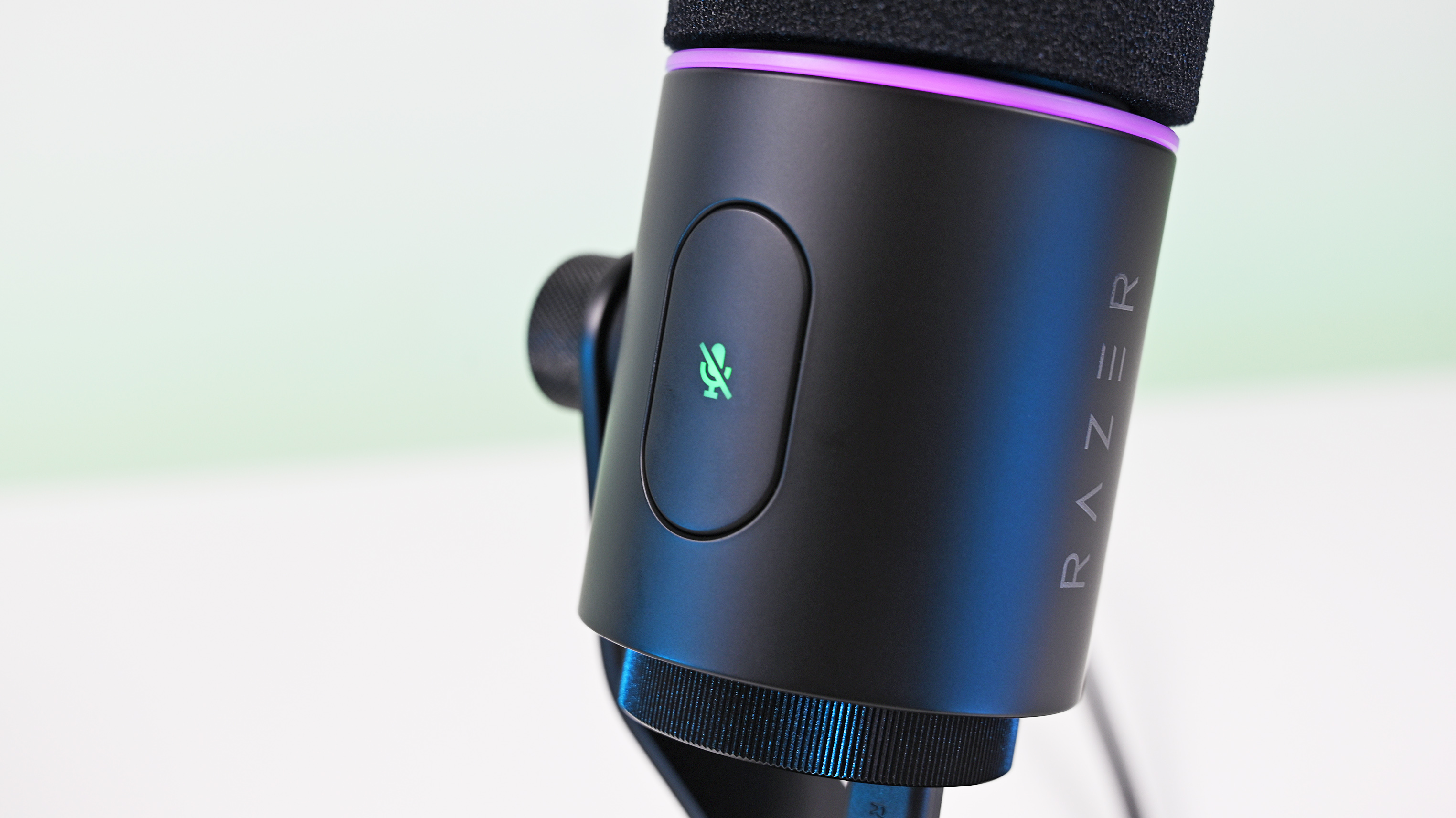Close-up of the Razer Seiren V3 Pro microphone housing, showing the glowing green tap-to-mute button icon and a purple LED ring.