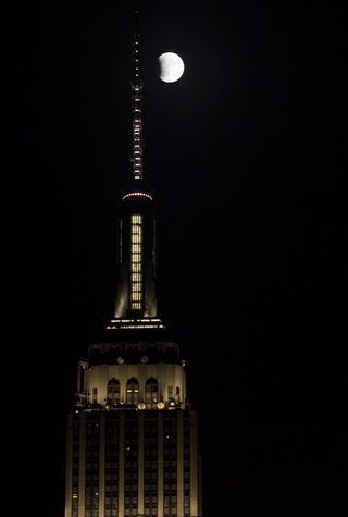 A perigee full moon, or supermoon, is seen hanging next to the Empire State Building at the beginning of a total lunar eclipse.