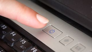 A person pressing the power button on their laptop.