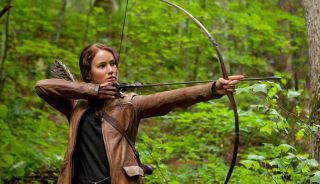 Jennifer Lawrence's Katniss Everdeen shooting an arrow in a forest in The Hunger Games