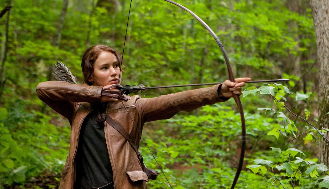 Jennifer Lawrence&#039;s Katniss Everdeen shooting an arrow in a forest in The Hunger Games