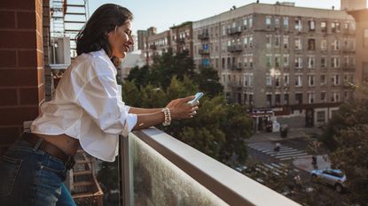 A single woman on a balcony outside her New York City apartment.