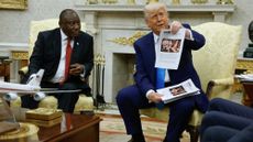 President Donald Trump holds up a printed article from "American Thinker" while accusing South Africa President Cyril Ramaphosa of state-sanctioned violence against white farmers in South Africa
