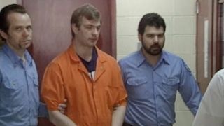 Jeffrey Dahmer being led in handcuffs in Conversations with a Killer: The Jeffrey Dahmer Tapes