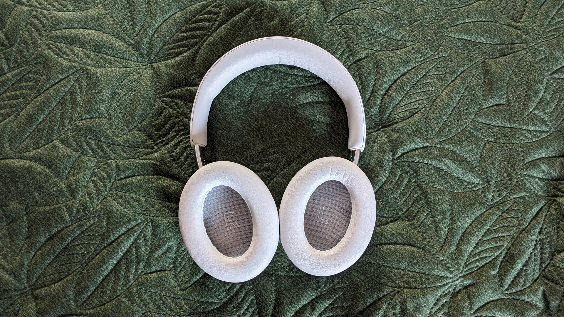 Bose QuietComfort Ultra Headphones (2nd Gen) noise-cancelling headphones on green fabric, inner earcups facing camera