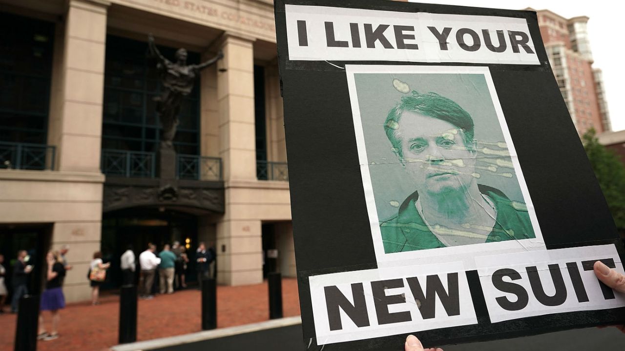 Protesters hold a poster of Paul Manafort outside court