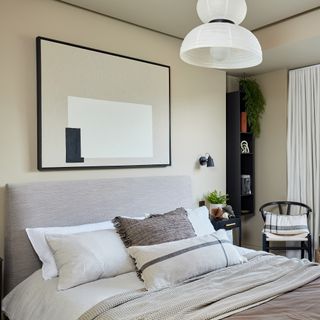 Neutral bedroom with graphic artwork and oversized, statement pendant light