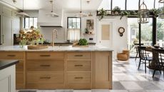 a large farmhouse kitchen with a stone checkerboard floor, large oak island with marble counter and a conservatory extension for dining