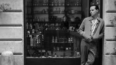 Black-and-white shot of Andrew Scott as Tom Ripley leaning against a shop window