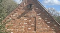 A bricked up window using recycled bricks with a bird hole above it