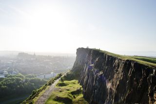 Edinburgh, Scotland, UK - June 18, 2016: Group of people standing at the Salisbury Crags. overlooking Edinburgh Castle.