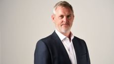 Pictured: Darktrace CIO Terry Doyle in a suit with white shirt and open collar.