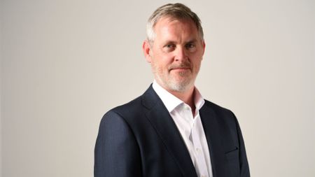 Pictured: Darktrace CIO Terry Doyle in a suit with white shirt and open collar.