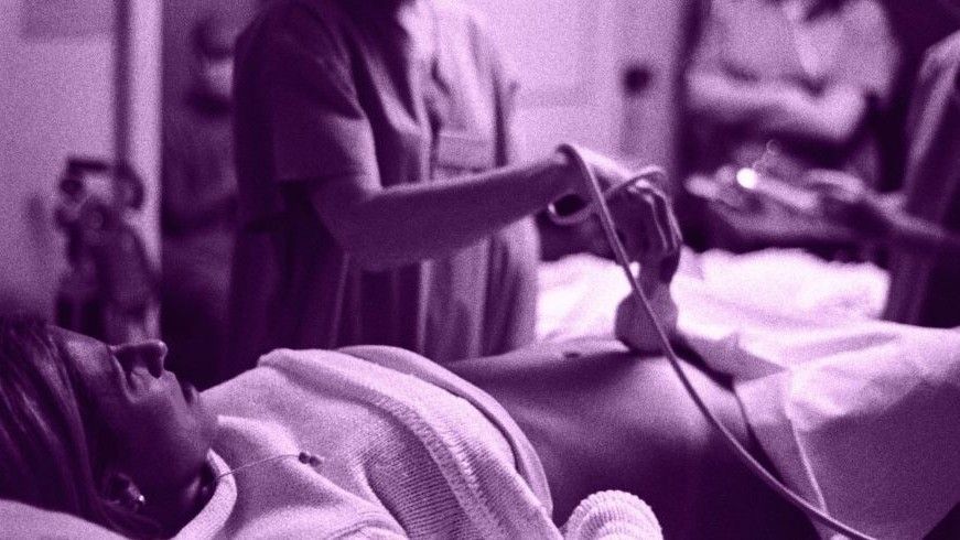 Medical person performing sonar on pregnant woman lying down