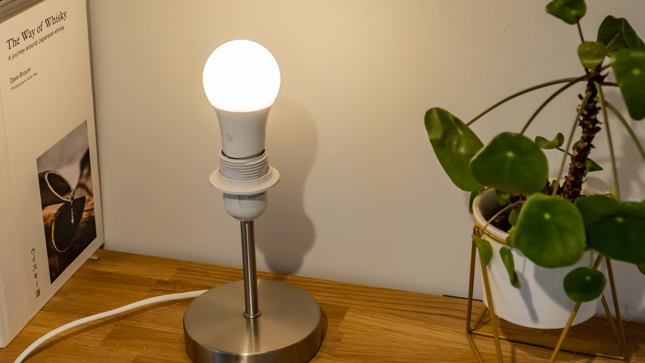 The Hive Smart Light Bulb illuminate white in a lamp on a shelf