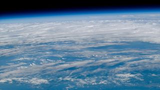 a view of Earth as seen from orbit with blue waters and white clouds set against the blackness of space