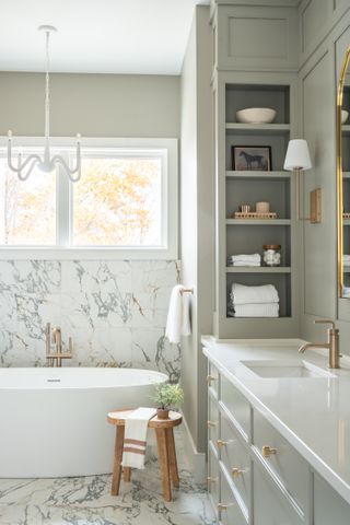 Gorgeous bathroom with marble floor, soft green walls, gold hardware